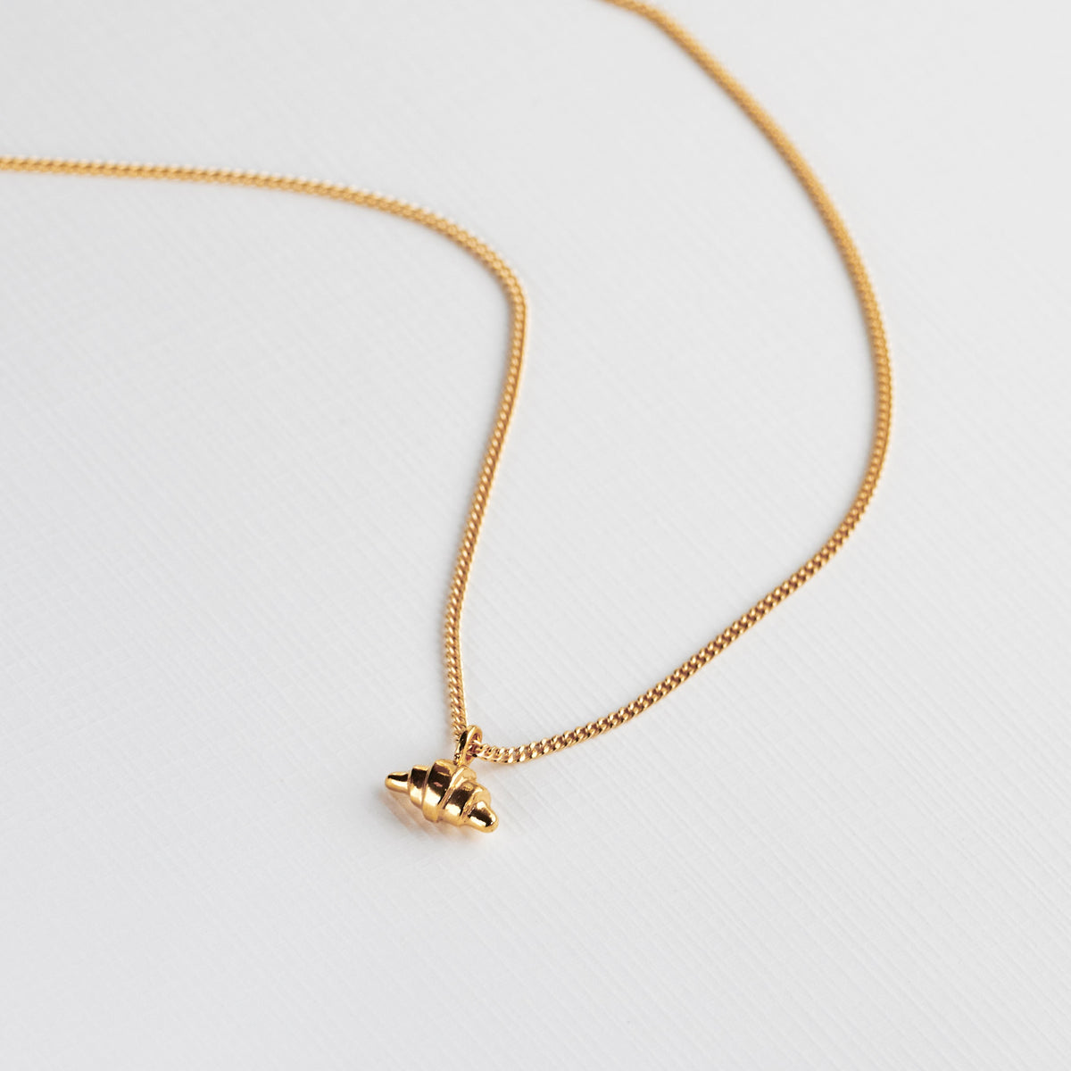 Gold croissant necklace on white background