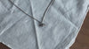 Silver croissant necklace on white linen